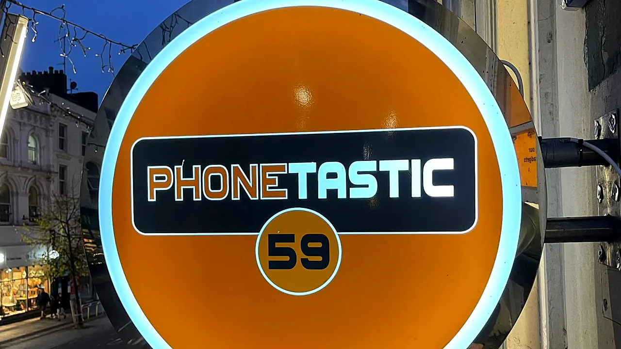 Round orange Phonetastic projecting light box with a glowing white edge, above a Cork street.