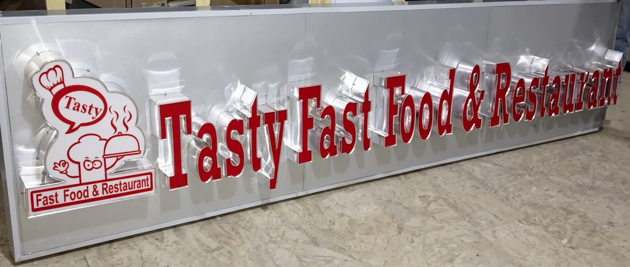 Long brushed aluminium sign panel with raised red letters reading Tasty Fast Food and Restaurant and a chef logo, finished in the workshop.